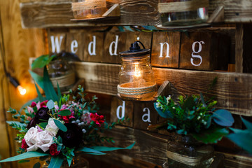 Wedding. Banquet. Mr. Mrs. signs on wooden board decorated by flowers and greenery and lounge zone including chairs and tables.