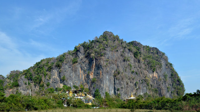 Panoramic view of the Bayin Nyi Cave complex in Hpa-An, Myanmar. Buddhist monastery, temple and lots of golden payas located near the foot of the big mountain.