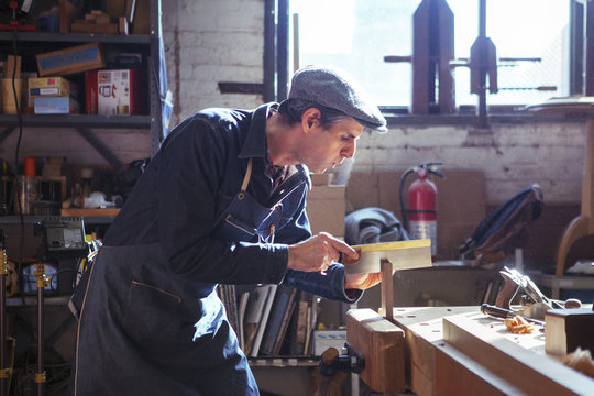 Carpenter Cutting Wood With Handsaw In Workshop