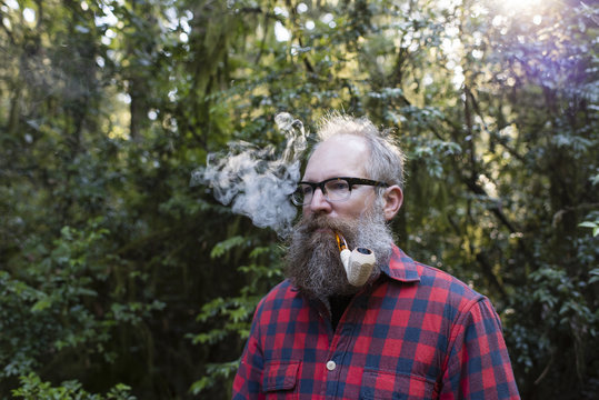 Man Smoking Pipe While Standing Against Trees