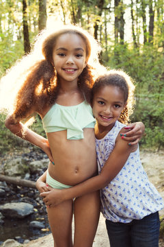 Portrait of girls standing at lakeshore in forest