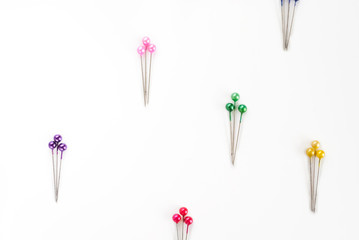 many colored sewing pins on white background