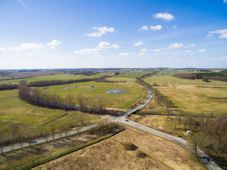 Fototapeta na wymiar Aerial view of a country road with crossing between agriculture fields and blue sky