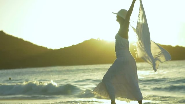 slow motion video of womas twirling sarong on tropical beach at sunset 