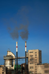 Old plant polluting atmosphere with two chimneys.