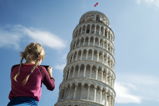 Rear view of girl photographing Leaning Tower of Pisa against sky