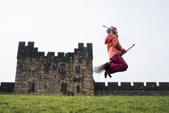 Side view of girl jumping with broom against castle