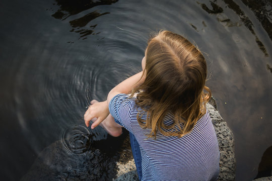 Overhead view of girl sitting on rock in lake