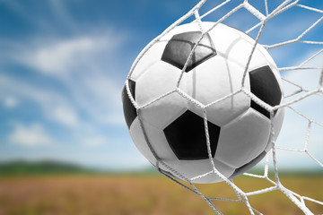 soccer ball in goal net with sky background