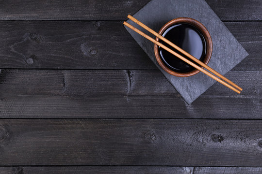 Background for sushi. Soy sauce, chopsticks on black stone. Top view with copy space