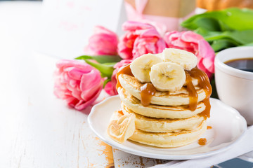 Fototapeta na wymiar Mother's day breakfast concept - pancakes, coffee, flowers, present