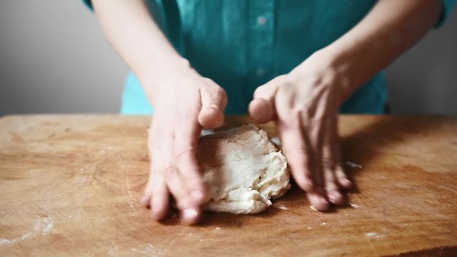 Woman hands kneading raw pie dough on wooden board in the kitchen. 