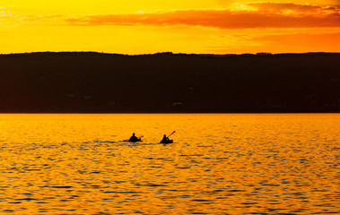  Kayakers paddle on Lake Superior against a vibrant golden sunset