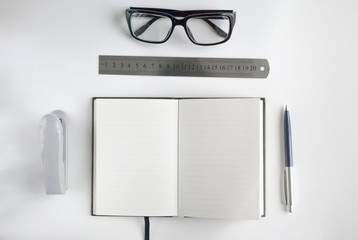 Office stationery such us glasses, pen, stapler, ruler and notebook for writing text