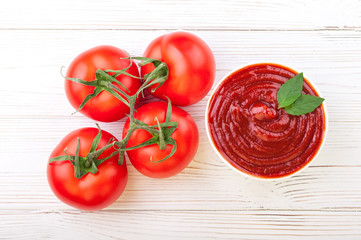 Tomato ketchup sauce in a bowl with basilic and tomatoes. Top view