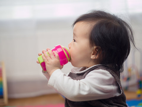 baby girl drinking water using a cup