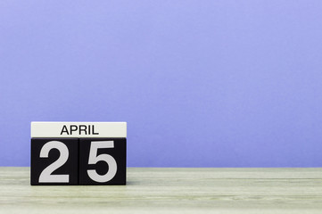 April 25th. Day 25 of month, calendar on wooden table and purple background. Spring time, empty space for text