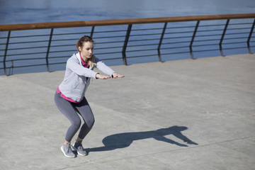 Morning exercise near the river. Young woman on recreation and jogging.
Warm up and stretch muscles before the morning exercise by the river