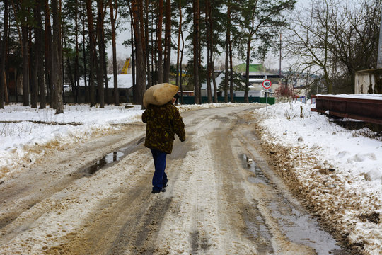 Man carries a large bag behind on the road in winter