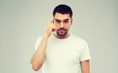 man with finger at temple over gray background