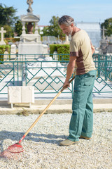 Man raking gravel in cemetery