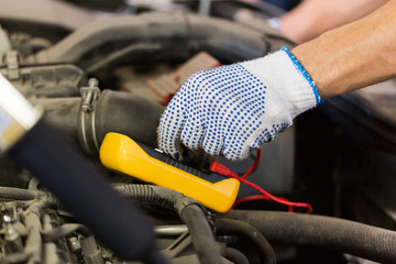 auto mechanic man with multimeter testing battery