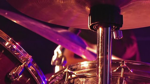 Drummer plays on drum set and cymbal with drumsticks on the stage. Jazz or rock concert performance entertainment. Close up shot with soft selective focus.