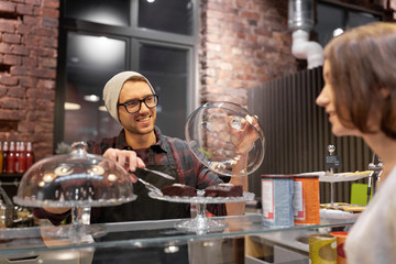 man or barman with cakes serving customer at cafe