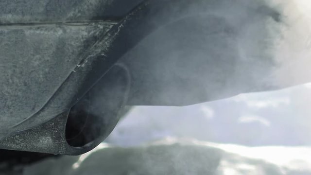Car pipe puffs out exhaust gas clouds. Smoke clouds coming out of automobile tailpipe. Air and environment pollution by vehicle closeup shot.