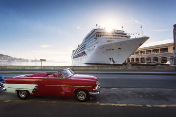Old car on street of Havana with cruise ship in background at sunrise, Cuba