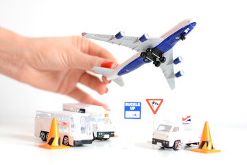 Travel concept with woman hand holding airplane toy above airport infrastructure