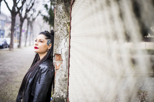 Daydreaming young woman leaning against wall
