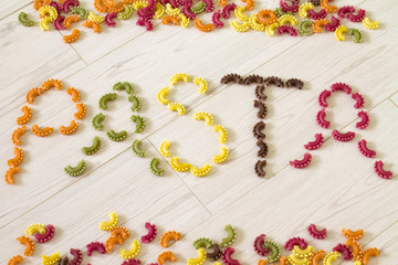 Written text "Pasta" from colorful raw pasta. (Beet, carrot, paprika, spinach, grape seed). 
