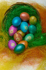 Happy Easter. Colorful Easter eggs in a basket on the artificial grass