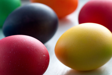 Colorful Easter eggs close-up macro on a white wooden table. The concept of a holiday and a happy Easter.