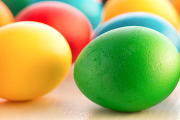 Colorful Easter eggs close-up macro on a white wooden table. The concept of a holiday and a happy Easter.