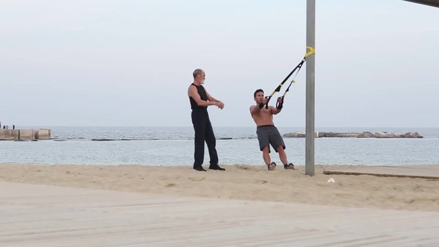 Schlingentraining mit Trainer am Strand