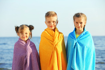 Cute kids wrapped in towel on beach