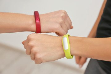 Fototapeta premium Hands of young women with fitness trackers, closeup