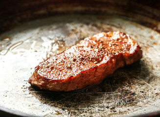 Delicious juicy steak on frying pan, closeup