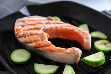 Cooking salmon steak and zucchini on grill pan