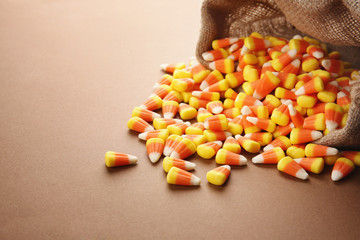 Sack with tasty Halloween candies on color background