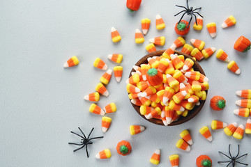 Bowl with colorful Halloween candies on light background