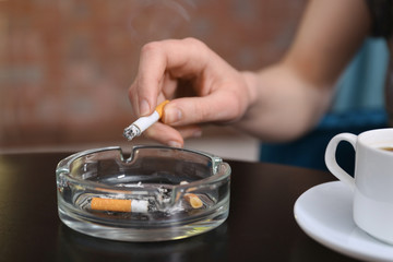 Smoking woman's hand holding cigarette sitting at table