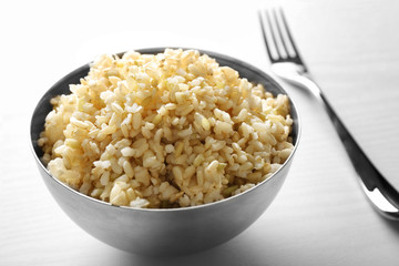 Bowl full of brown rice on white background