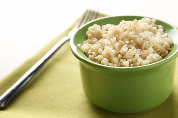 Green ceramic bowl full of brown rice on napkin