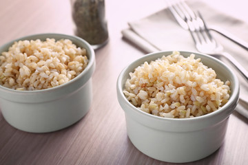 Two bowls of brown rice on wooden table