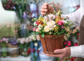 Male florist holding basket with flowers in flower shop, closeup