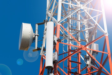 Mobile phone communication antenna tower with satellite dish on blue sky background