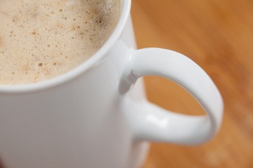 Close-up of white mug of coffee with creamy froth